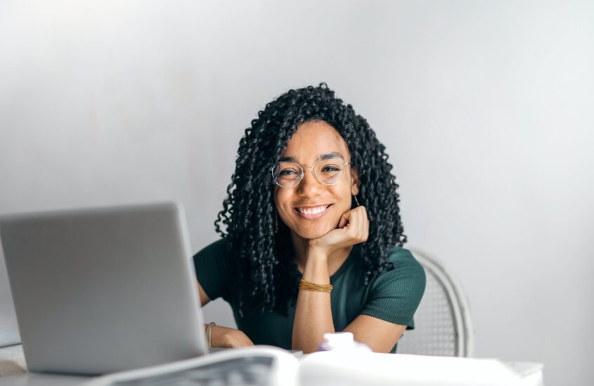 happy ethnic woman sitting at table with laptop