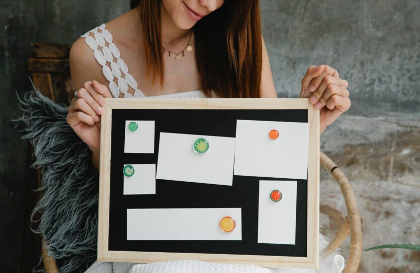 smiling woman showing noticeboard with blank papers